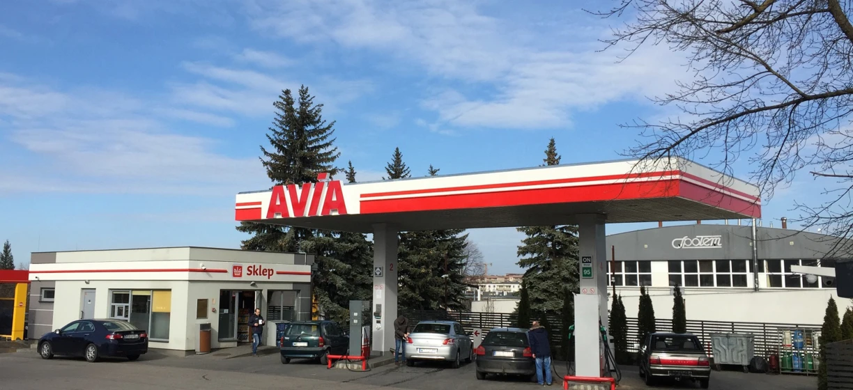 Luksusowy pojazd zaparkowany przy stacji paliw. Znak sklepu AVIA po polsku. Samochód rodzinny tankuje paliwo.